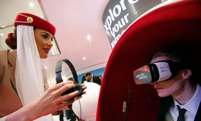 Flight attendant assists visitor using virtual reality headset at Emirates Airlines stand during ITB in Berlin