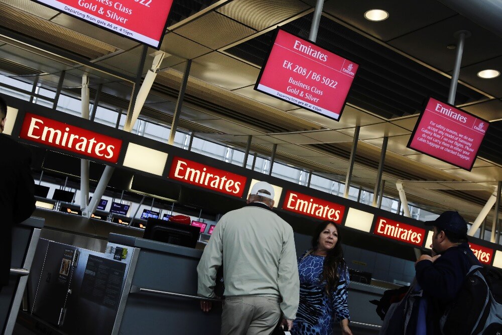 Travelers wait at an Emirates Airlines ticket desk at JFK International Airport in New York