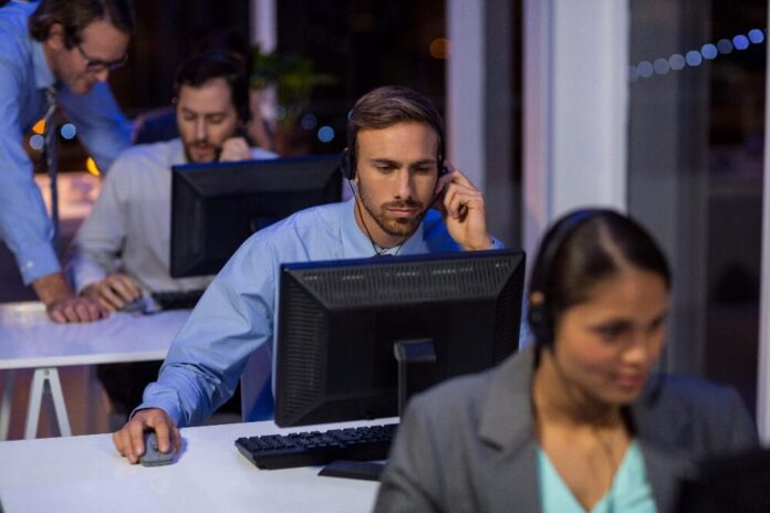 Businessman with headsets using computer in office at night