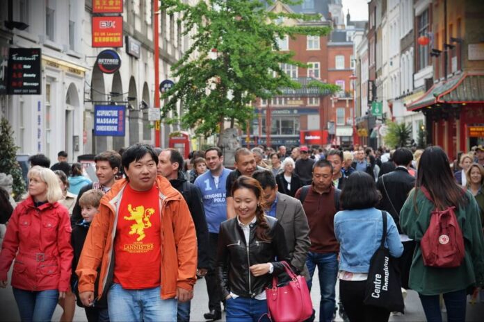 People walk along a busy shopping street in London's Chinatown