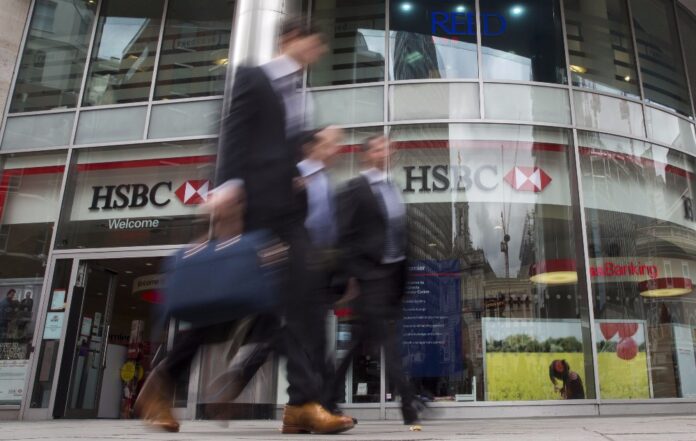 Workers walk past a branch of HSBC bank in central London