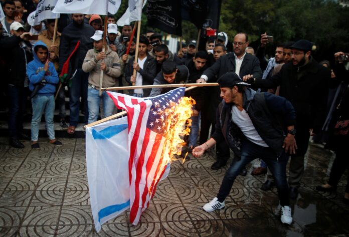 Palestinians burn an Israeli and a U.S. flag during a protest against the U.S. intention to move its embassy to Jerusalem and to recognize the city of Jerusalem as the capital of Israel, in Gaza City
