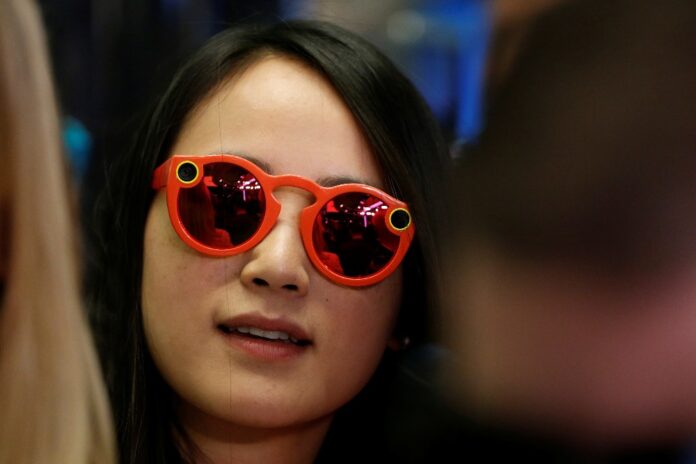 A woman wears Snapchat Spectacles on the floor of the New York Stock Exchange (NYSE) while waiting for Snap Inc. to list their IPO in New York