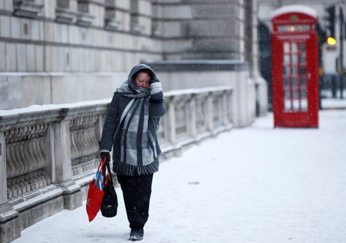 A woman walks through the snow storm in central London