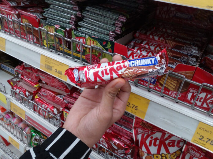 Hand hold a packet of NESTLE Kit Kat mini mocha chocolate wafer in supermarket.