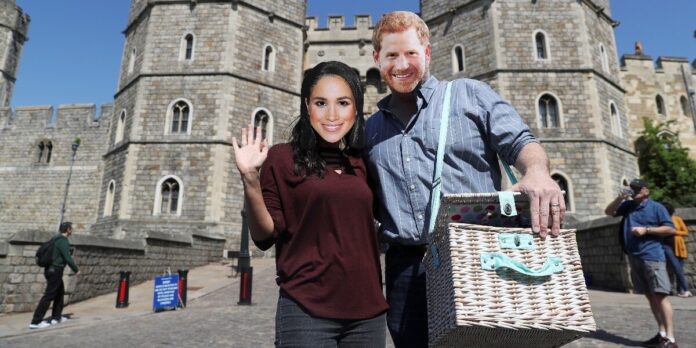 A couple wear Prince Harry and Meghan Markle face masks outside Windsor Castle in Windsor