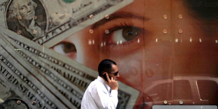 A man walks past an exchange bureau advertisement showing images of the US dollar in Cairo
