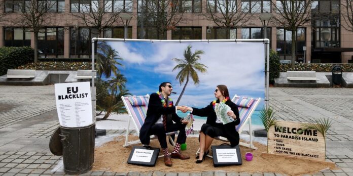 Activists stage a protest on a mock tropical island beach representing a tax haven outside a meeting of European Union finance ministers in Brussels