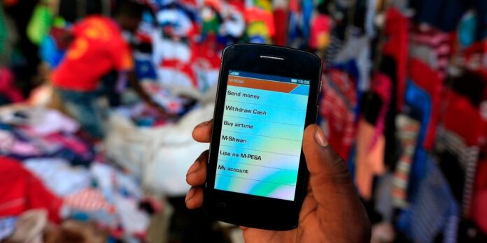 Man holds up his mobile phone showing a M-Pesa mobile money transaction page for the photographer at an open air market in Kibera in Kenyas capital Nairobi