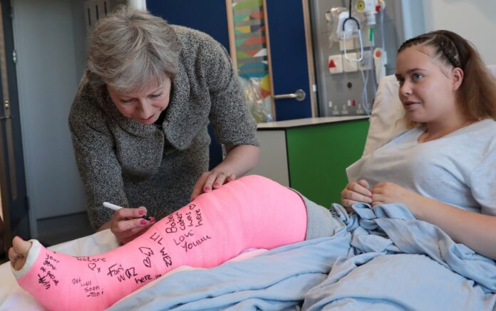 Britains Prime Minister Theresa May signs the cast of patient Jade Myers 15 of London who broke her leg falling off a wall during a visit the Royal Free Hospital in London