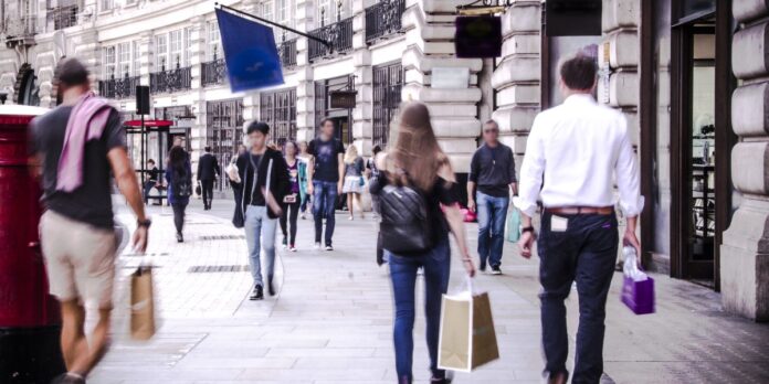 Anonymous shoppers walking down busy London shopping street