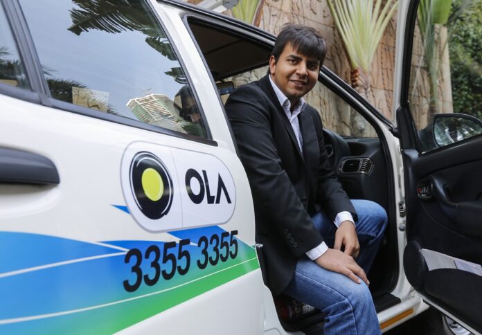 Bhavish Aggarwal, CEO and co-founder of Ola, an app-based cab service provider, poses in front of an Ola cab in Mumbai - Image: REUTERS/Shailesh Andrade